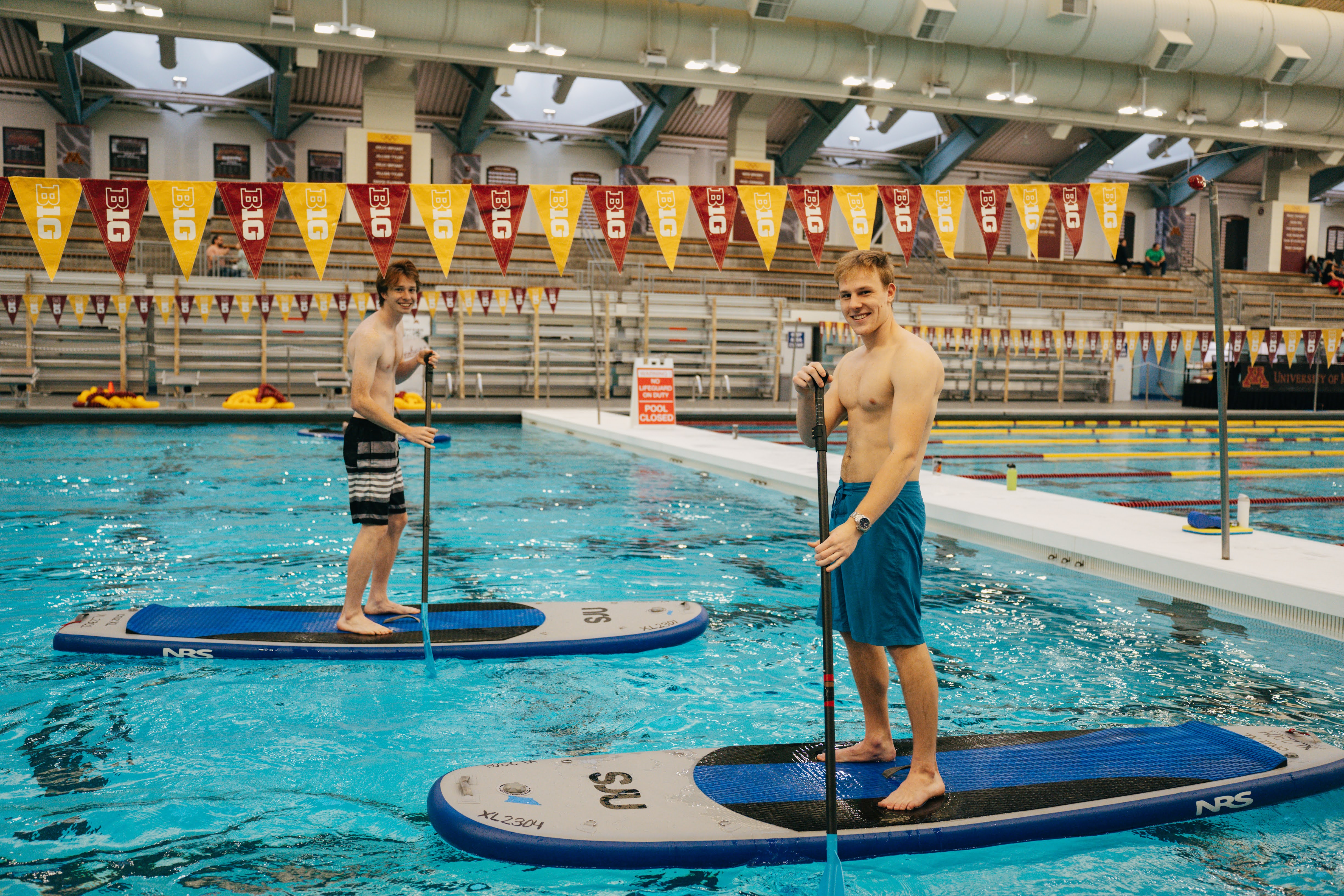 two students using standup paddle boards