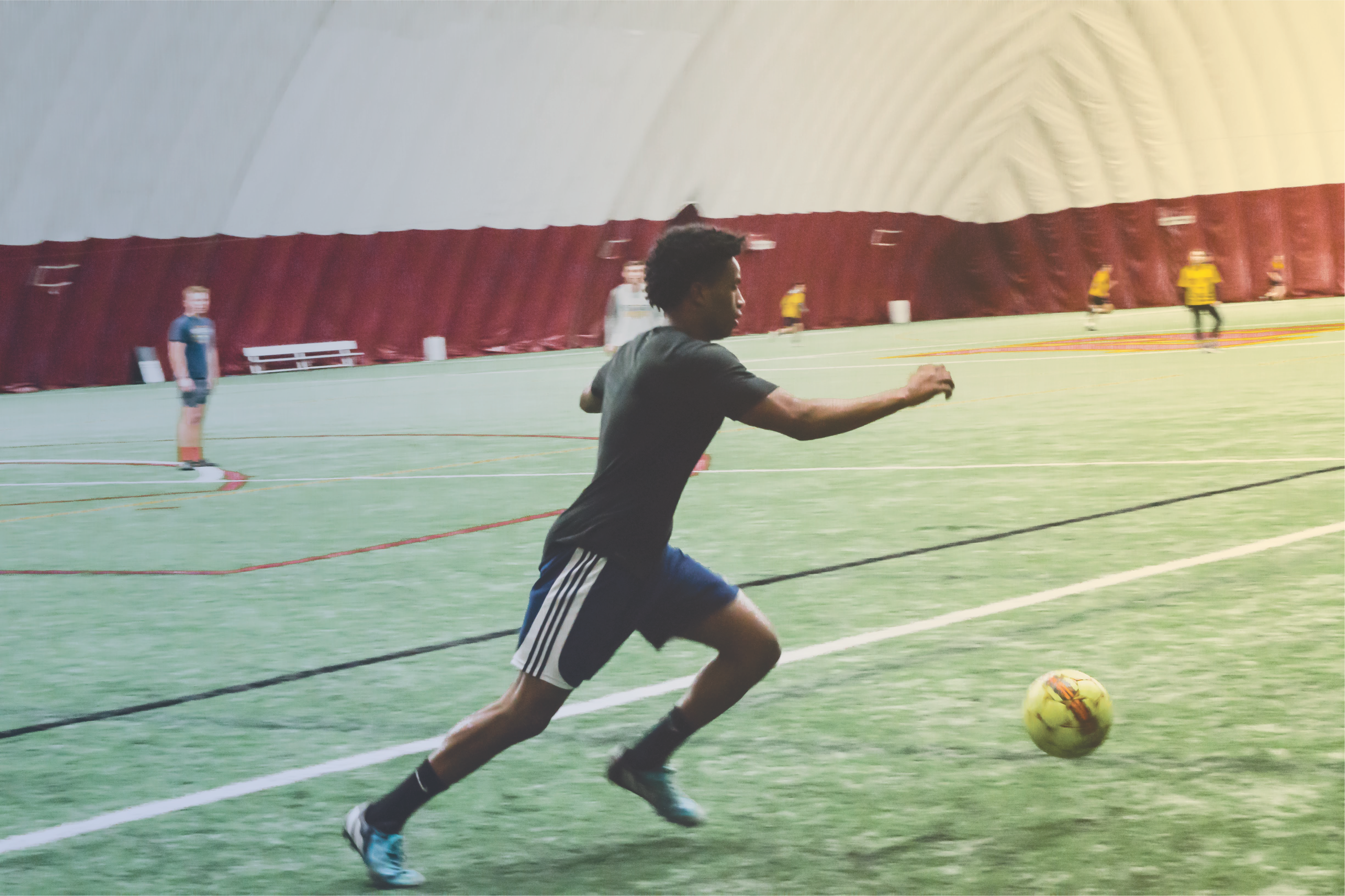 Student running after soccer ball in the dome