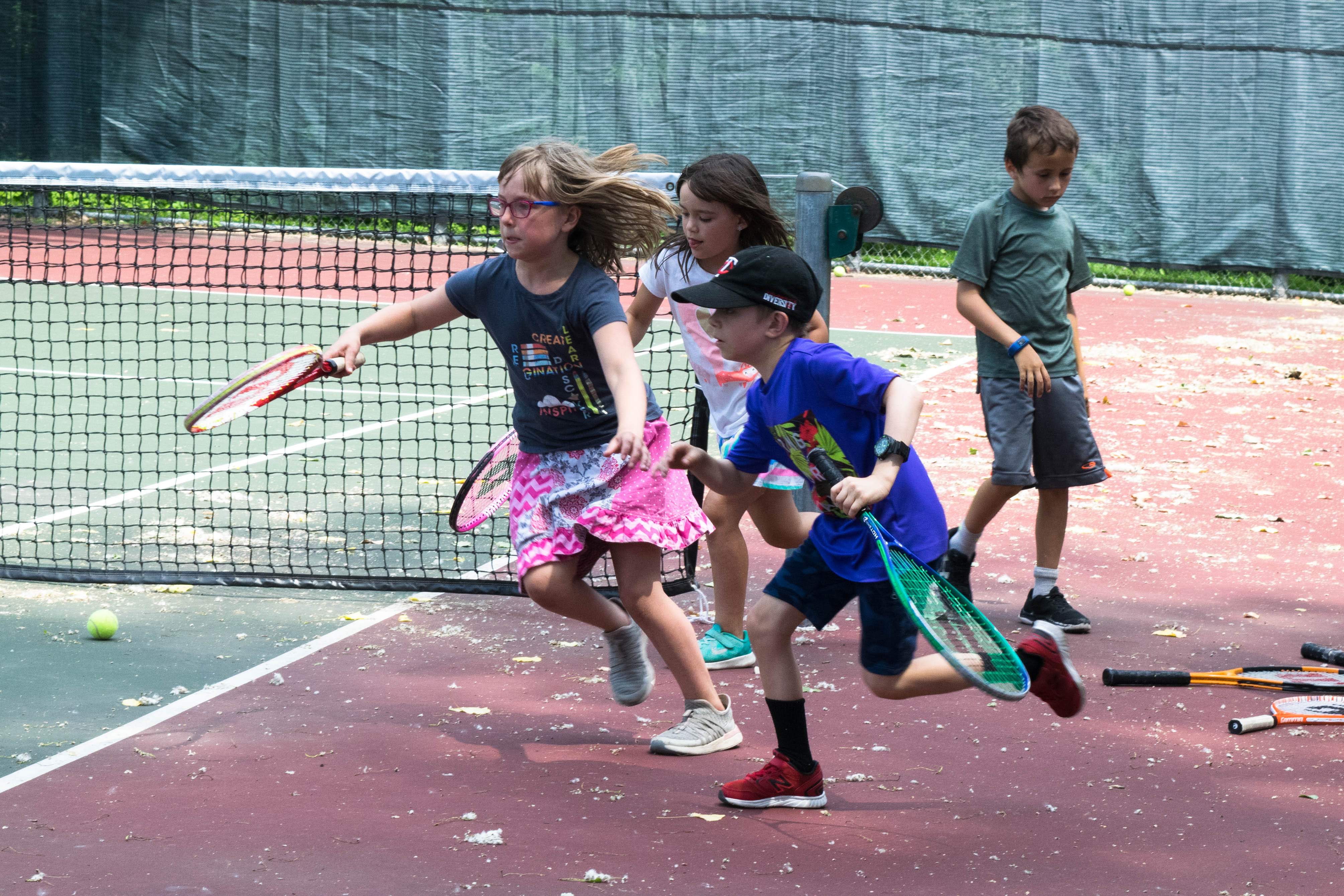 Four children running on tennis court
