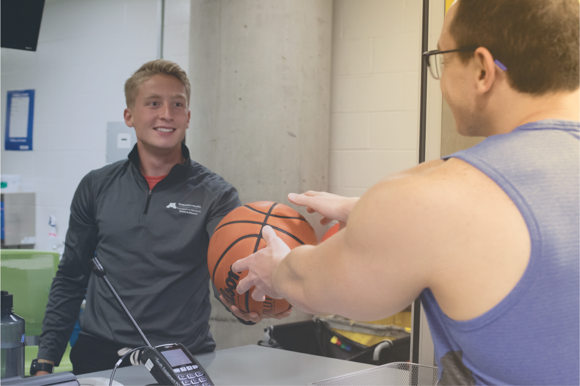 Student staff handing basketball to another student