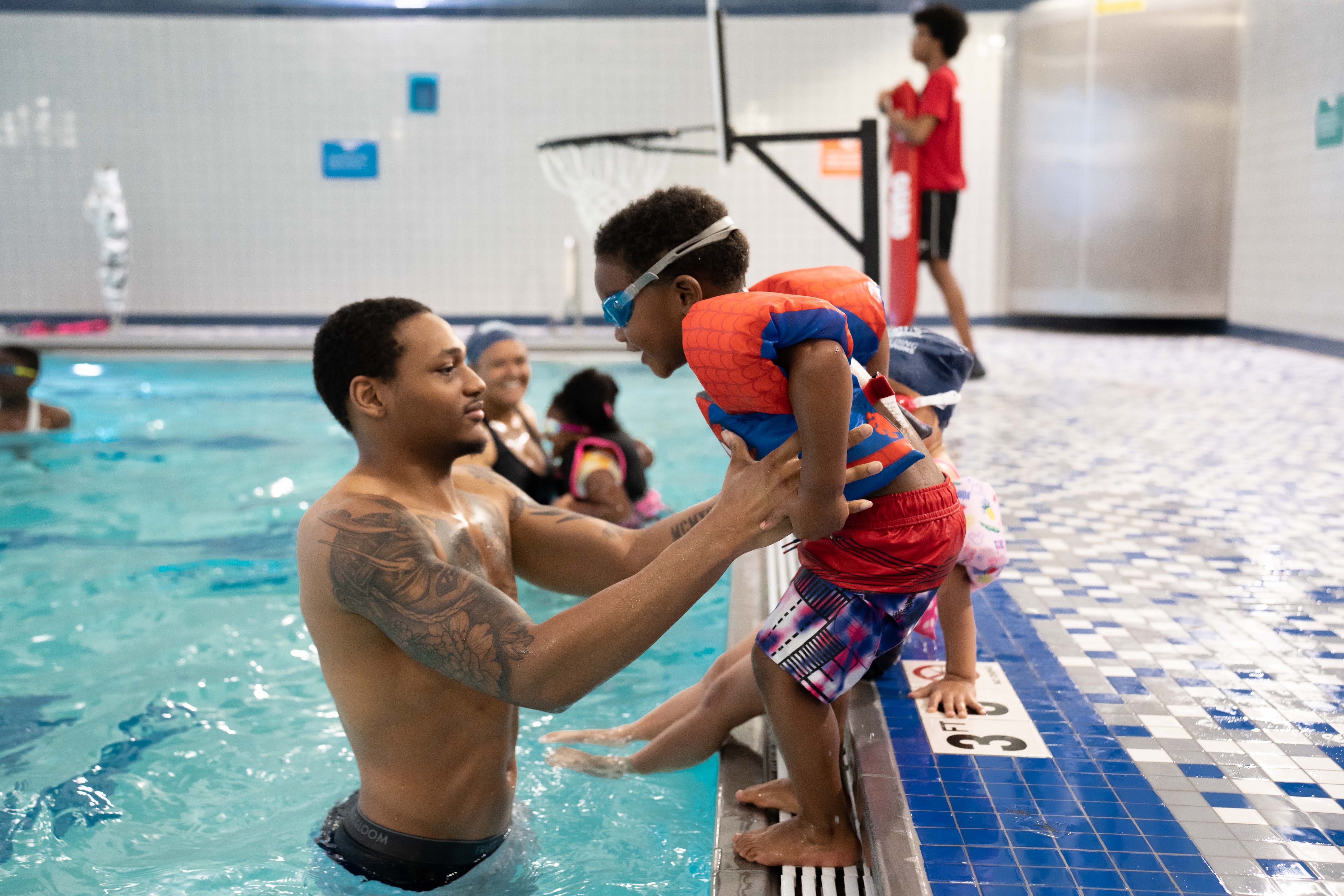 learn to swim participant jumping into pool with help