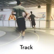two students running around the indoor track
